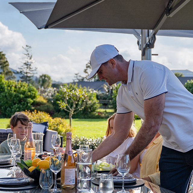 Father placing food on table under a Harmony Umbrella